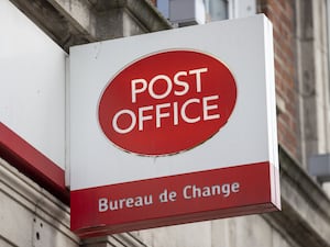 White and red shop sign reading Post Office and Bureau de Change