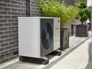 A heat pump alongside the brick wall of a home