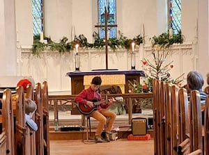 Ollie Hodge playing his guitar in the concert.