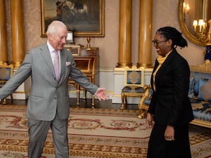 The King holds his arms wide as he greets a smiling Kemi Badenoch