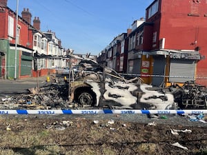 A burnt out vehicle in the Leeds suburb of Harehills (Katie Dickinson/PA)