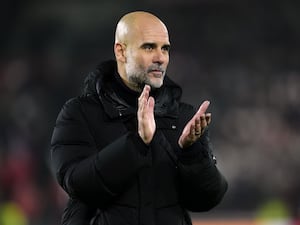 Pep Guardiola, dressed in black, applauds after a game