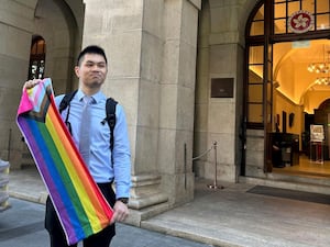 Nick Infinger, who won a lengthy legal battle over the differential treatment facing same-sex couples, holds up a rainbow banner after speaking to the media outside Hong Kong’s top court