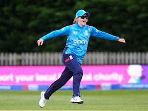 Charlie Dean holds her arms out by her side to celebrate a wicket