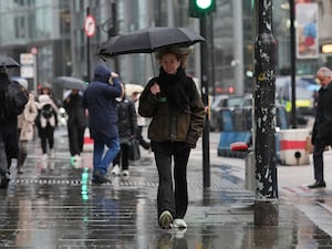 People walking along a pavement under umbrellas during a rain shower