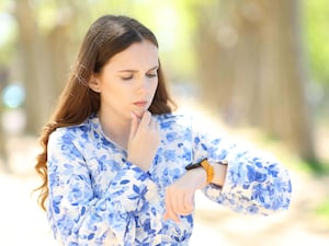 A woman in a blue shirt looking worriedly as her smartwatch