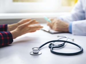 A doctor and patient talking with a stethoscope between them