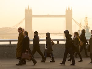 People in shadow walking past Tower Bridge in London