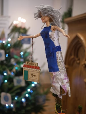 Is it is Christmas fairy or a doll of Sharon Harris, the owner of Esco’s shop on their tree?