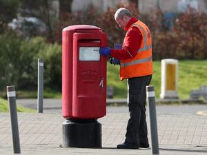 A Royal Mail worker empties a postbox