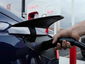 A motorist charges his electric vehicle at a Tesla Supercharger station