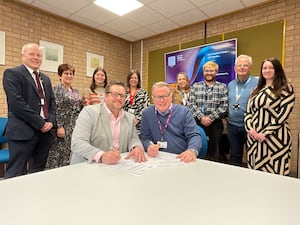 Matt Gofton of CIPD (front left) and Paul Bradshaw, Powys County Council’s Head of People (front right) signing the People Development Partnership agreement, watched by members of Powys County Council’s People team.