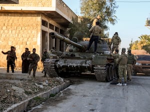 Opposition fighters stand on top of a captured Syrian army armoured vehicle in the town of Maarat al-Numan, south-west of Aleppo