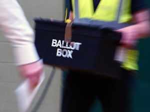 A ballot box being held by a man in a hi-viz vest