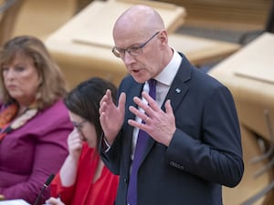 John Swinney gesturing with his hands during a speech