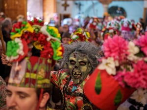 A masked devil among a colourful parade