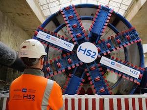 An HS2 worker in hi-vis jacket and hard hat stands in front of one of the project's tunnel boring machines