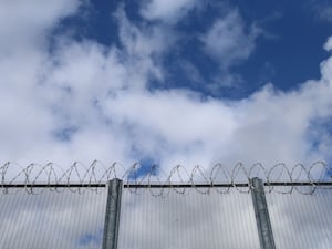 A prison fence with blue sky above