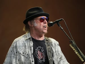 Neil Young wearing a trilby and singing a song