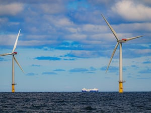 A ship passing two offshore wind turbines