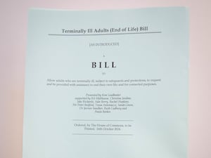 A person holds a hard copy of the Terminally Ill Adults (End of Life) Bill