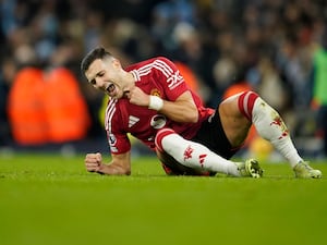 Diogo Dalot clenches his fists to celebrate while laid on the floor