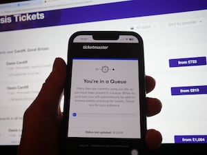 The hand of a person in a queue to access the Ticketmaster website on their phone