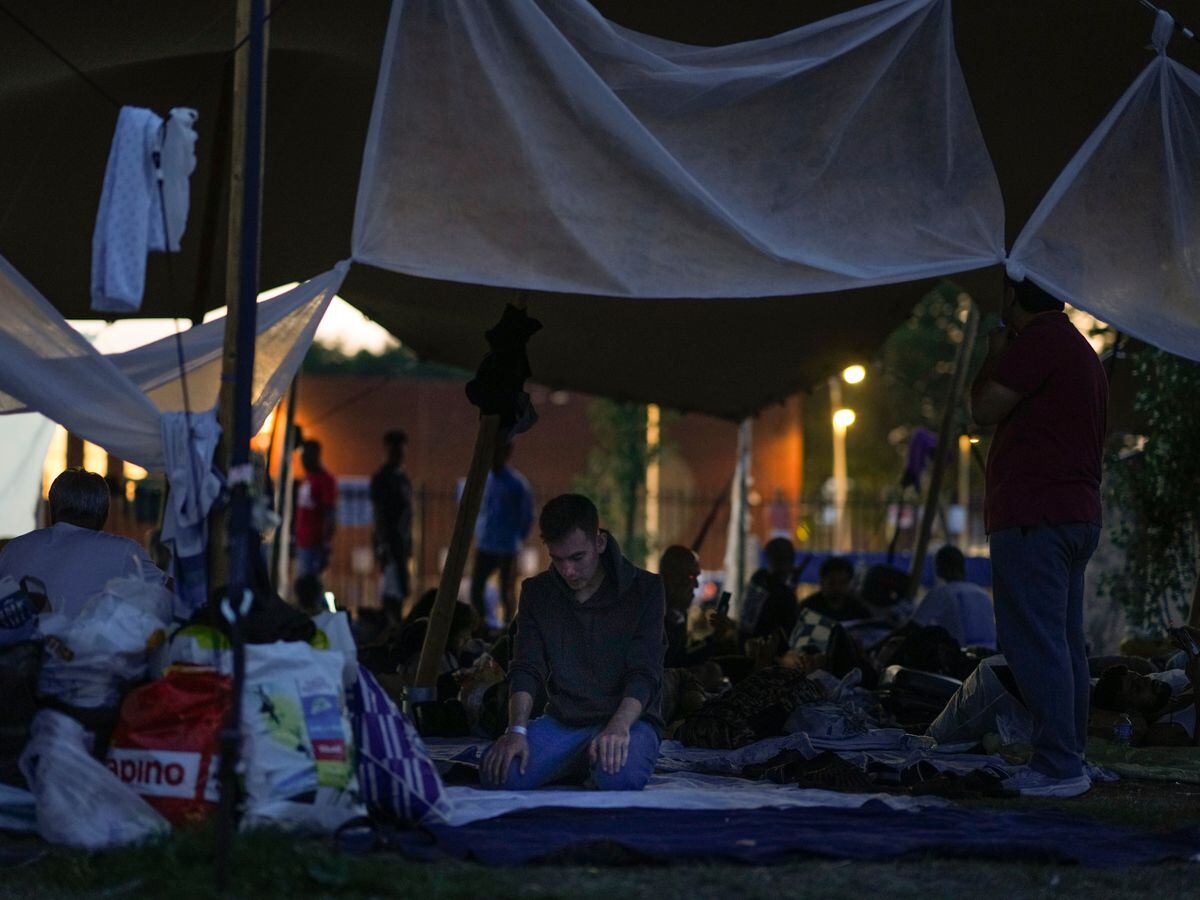 A man prays under a tarpaulin as hundreds of migrants prepare to spend the night outside an overcrowded asylum seeker centre in Ter Apel, northern Netherlands