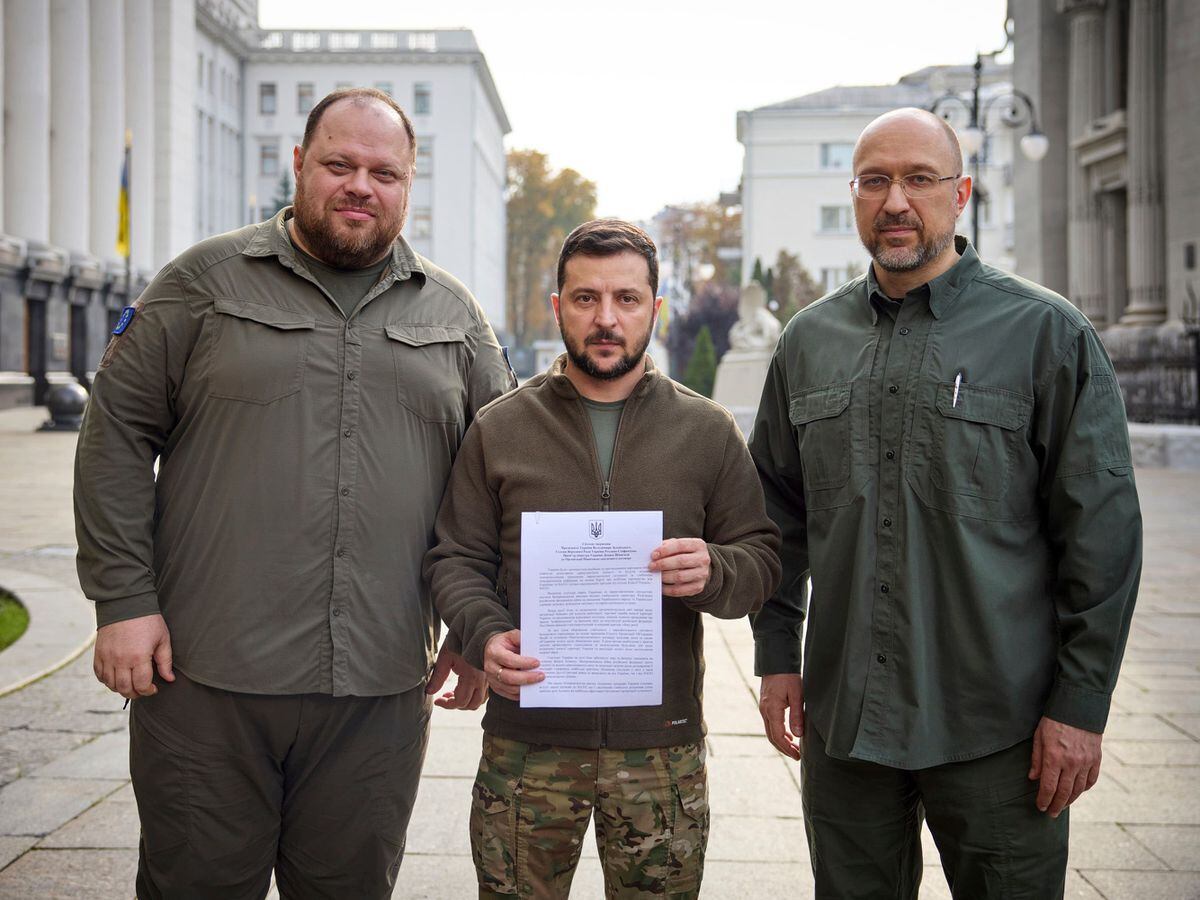 Ukrainian president Volodymyr Zelensky, centre, holds an application for 'accelerated accession to Nato' in Kyiv